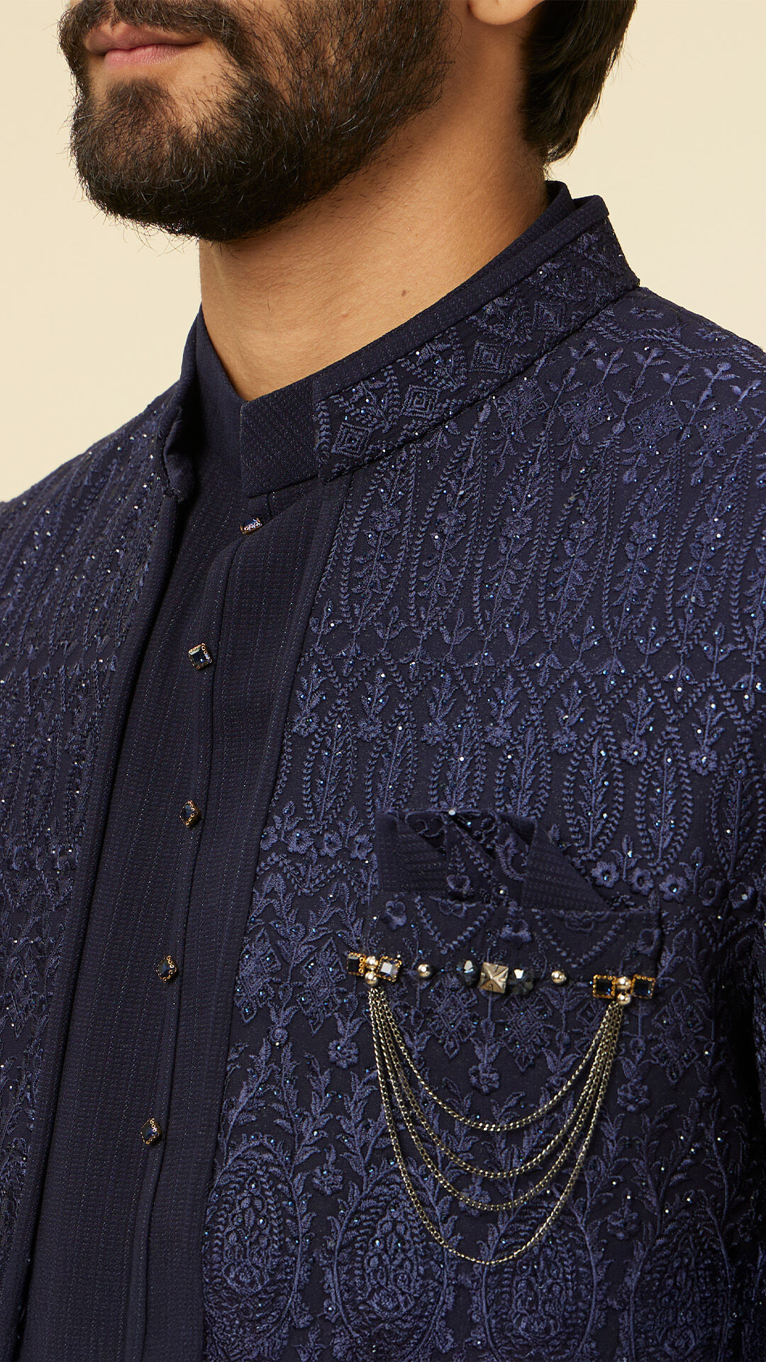 A groom in blue sherwani with a gold brooch on pocket 